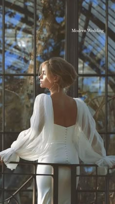 a woman in white is looking out the window with her back turned to the camera