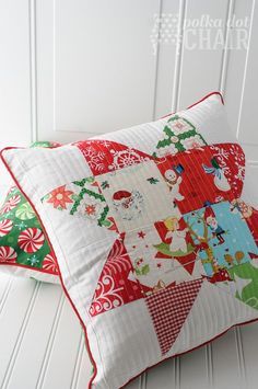 two red and green pillows sitting on top of a white table next to each other