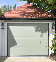 a white garage with a red roof and two lights on the side of the garage