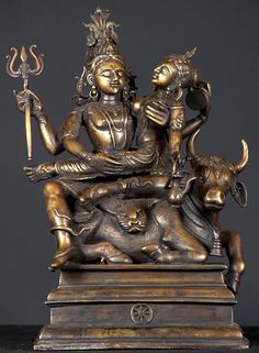 a bronze statue with an animal on it's back and two people sitting on the other side