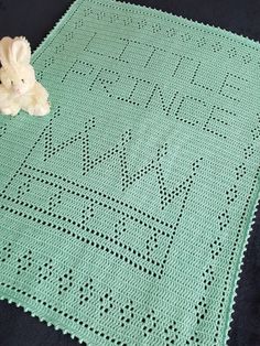 a teddy bear sitting on top of a green crocheted blanket