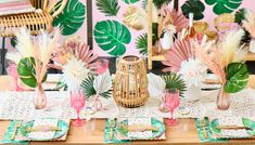 the table is set with pink and green plates, napkins, and vases