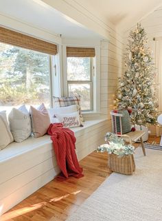 a decorated christmas tree in the corner of a room with white walls and wood floors