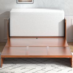 the bed frame is made from wood and has a white mattress on top of it