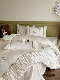 a bed with white comforter and pillows on it in a room next to a lamp