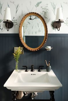 a white sink sitting under a mirror next to a wall mounted faucet in a bathroom