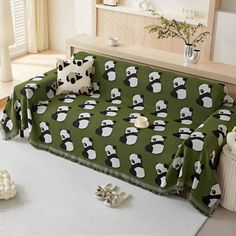 a living room with a green couch covered in panda bears