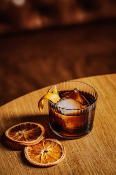 an old fashioned drink with orange slices on the table