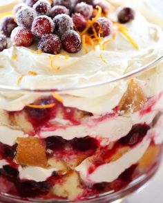 a layered dessert in a glass dish with cranberries and orange zest