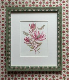 a pink flower is framed in a green frame on a floral wallpapered background