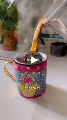 a person pouring liquid into a cup on top of a white counter next to a potted plant