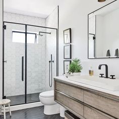 a bathroom with black and white tile flooring, wooden vanity, and shower stall