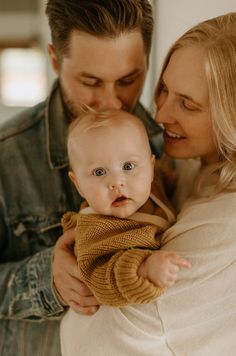 a man and woman holding a baby in their arms