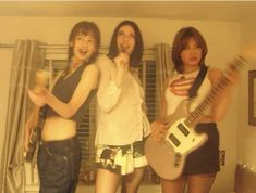 three young women standing next to each other holding guitars