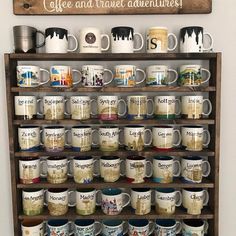 coffee and travel adventure mugs are displayed on an old wooden shelf in front of a sign