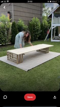 a woman bending over to check out a table on the ground in front of a house