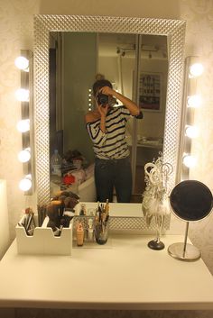 a woman taking a selfie in front of a vanity mirror with makeup on it