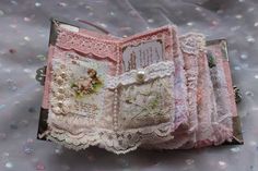 an open book with lace and pearls on the inside is sitting on a bed covered in sequins