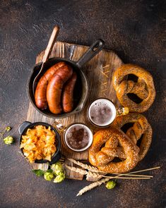 a wooden tray topped with pretzels, onion rings and two mugs of beer