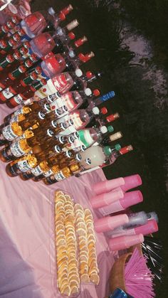 a table topped with lots of bottles of alcohol next to a pink cloth covered table