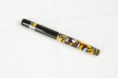 a pen that is sitting on top of a white surface with yellow and brown designs