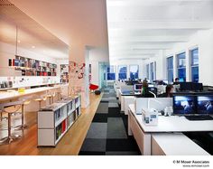 an office filled with desks and computers next to each other in front of large windows