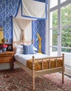 a bedroom with blue and white wallpaper has a bed in the middle, along with a rug on the floor