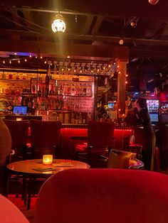 a dimly lit bar with red chairs and tables