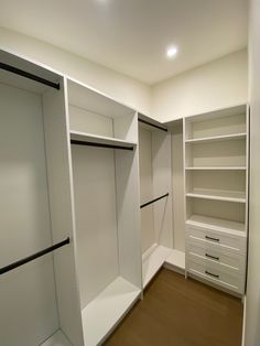 an empty walk in closet with white shelves and drawers