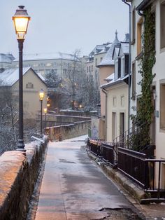 a street light sitting on the side of a road next to tall buildings covered in snow