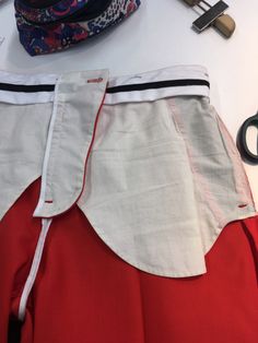 a pair of scissors sitting on top of a table next to a red and white skirt