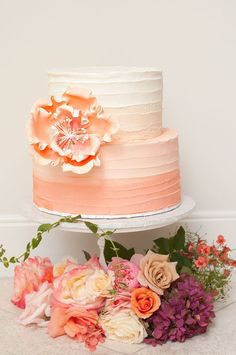 two tiered wedding cake with flowers on the top and bottom, sitting next to each other