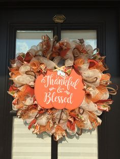 an orange and white wreath with the words, grateful and blessed on it in front of a black door