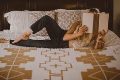 a woman laying on her bed reading a book