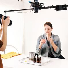 two women sitting at a table with bottles in front of them and one holding a camera