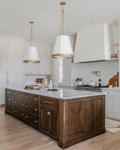 a large kitchen with an island in the middle and two pendant lights hanging from the ceiling