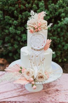 a white wedding cake with pink flowers and feathers