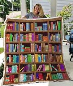 a woman is holding up a quilt made out of books on a bookcase outside