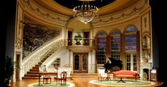 the stage is set for a play with furniture and chandelier in front of a grand piano