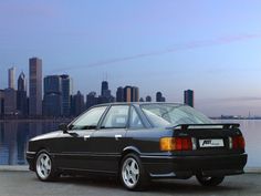 a black car parked in front of a city skyline