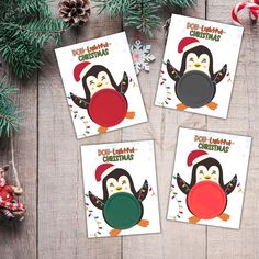 three penguin christmas cards on a wooden table with pine cones and candy canes in the background