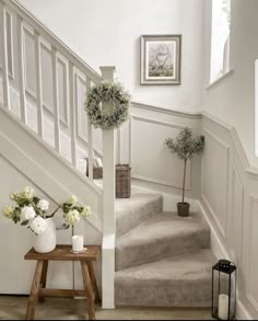 some flowers are sitting on the stairs in this white house with wood flooring and railings