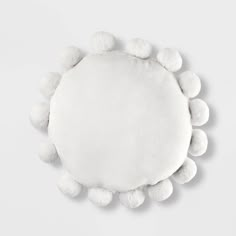 a white round pillow with pom - poms on the sides and one side