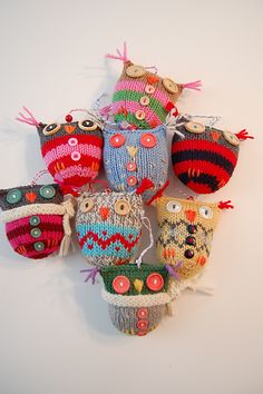 an assortment of knitted owls sitting on top of each other in front of a white wall