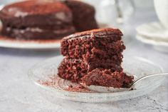 a piece of chocolate cake on a plate with a fork in front of the slice