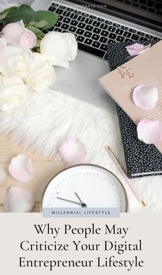 a laptop computer sitting on top of a desk next to pink flowers and a clock