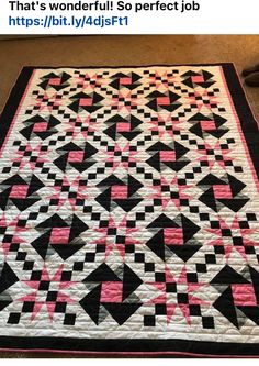 a black and white quilt with pink squares on it