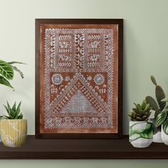 a wooden frame with an intricate design on it next to potted plants and other decorative items