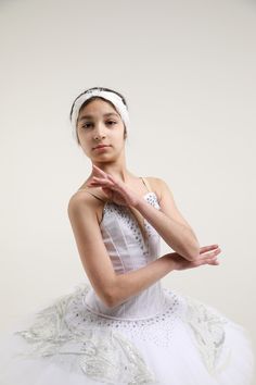 a woman in a white dress is posing for the camera with her hands folded up