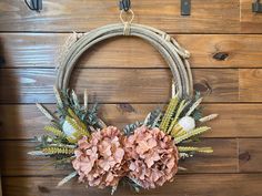 a wreath with pink flowers hanging on a wooden wall in front of a wood paneled wall